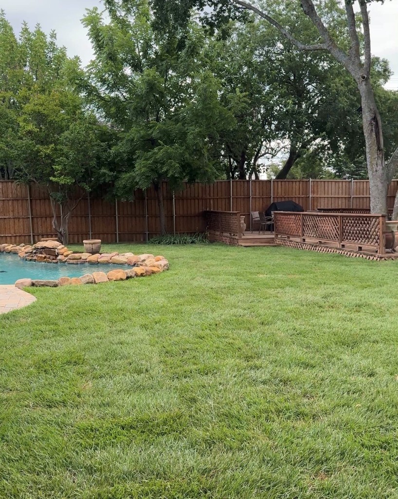 Same backyard with a thick, healthy green lawn after irrigation installation